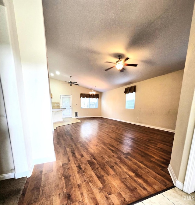 unfurnished living room with ceiling fan, a textured ceiling, baseboards, and wood finished floors