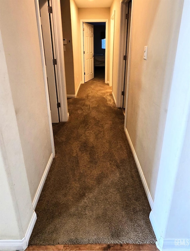 hallway with carpet flooring and baseboards