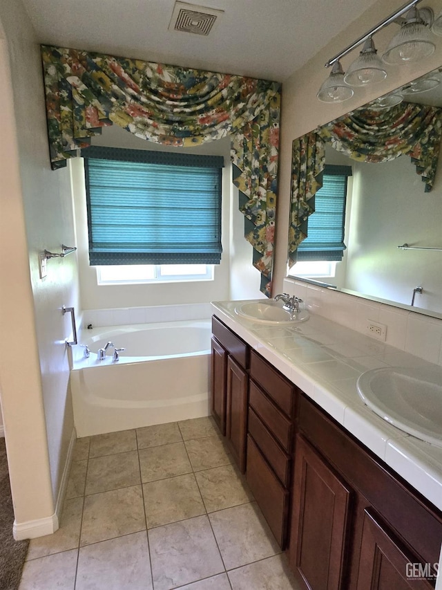 bathroom with double vanity, visible vents, a garden tub, tile patterned flooring, and a sink