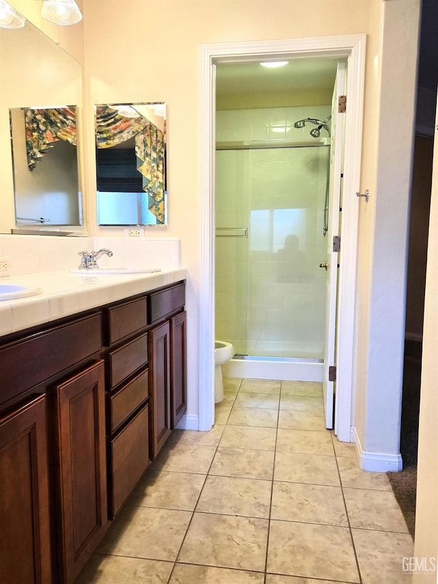 bathroom featuring double vanity, toilet, tile patterned flooring, a shower stall, and a sink