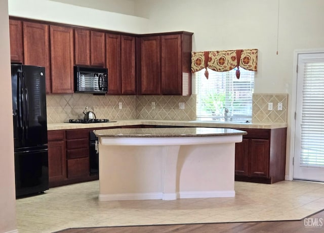 kitchen with a sink, a kitchen island, backsplash, black appliances, and plenty of natural light