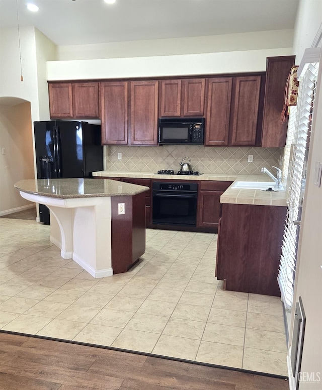 kitchen featuring black appliances, a kitchen island, a sink, and backsplash