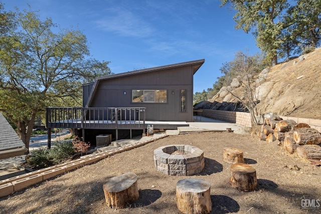 rear view of property featuring a deck, central AC, and an outdoor fire pit