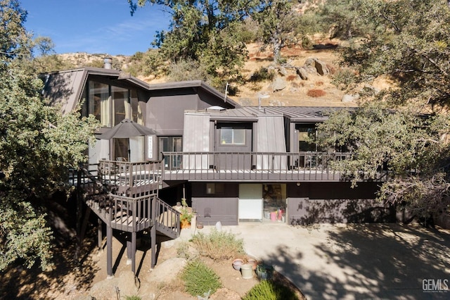 back of property with a wooden deck, metal roof, stairway, and a standing seam roof