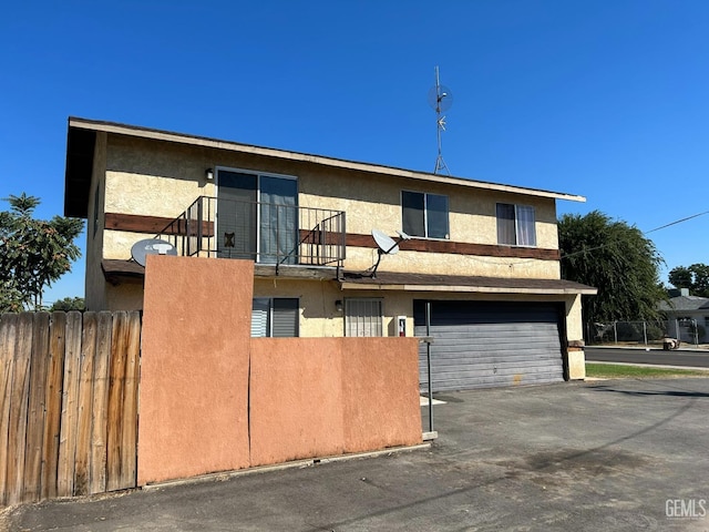 multi unit property with an attached garage, fence, and stucco siding