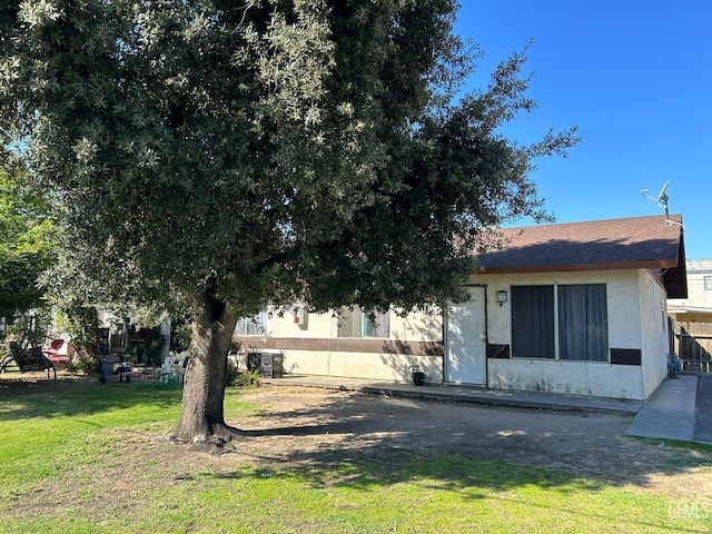 rear view of house with a yard and stucco siding