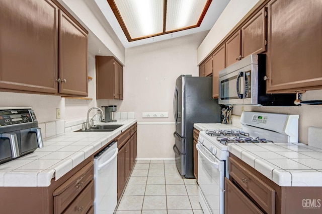 3304 Charlotte St, Bakersfield, CA 93313 - kitchen with white gas stove, dishwashing machine, stainless steel microwave, light tile patterned floors, and tile countertops