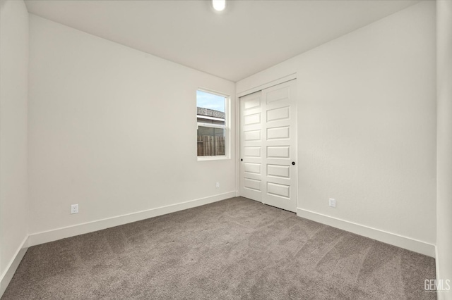 unfurnished room featuring carpet and baseboards