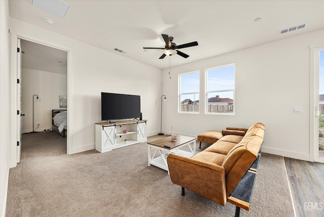 carpeted living room featuring a ceiling fan, visible vents, and baseboards