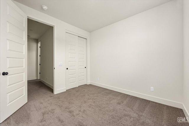 unfurnished bedroom featuring a closet, baseboards, and carpet