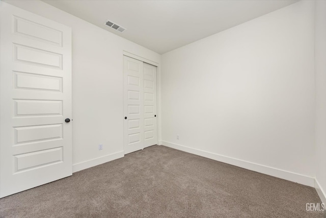 unfurnished bedroom with visible vents, baseboards, a closet, and carpet flooring