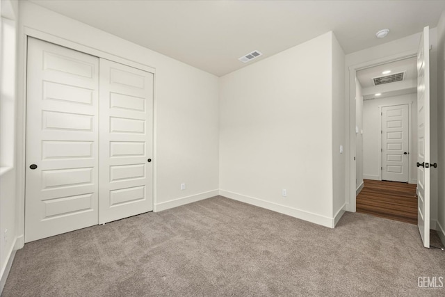 unfurnished bedroom with visible vents, baseboards, carpet, and a closet