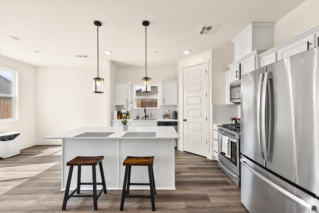 kitchen with visible vents, a center island, a kitchen breakfast bar, stainless steel appliances, and a sink