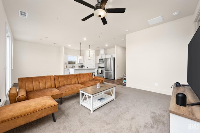 carpeted living area with recessed lighting, a ceiling fan, visible vents, and baseboards