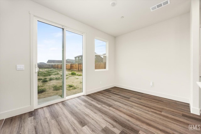 spare room with visible vents, baseboards, and wood finished floors