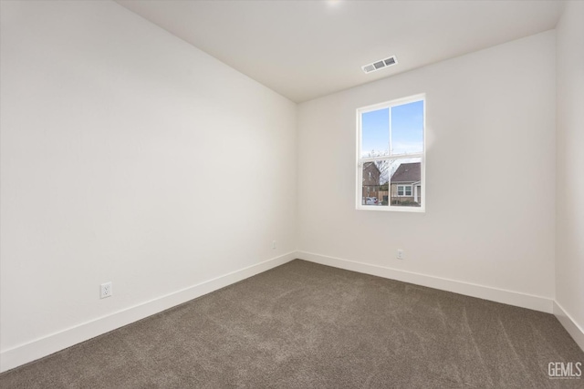 empty room featuring baseboards, visible vents, and dark carpet