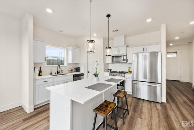 kitchen with a sink, a center island, white cabinets, stainless steel appliances, and dark wood-style flooring