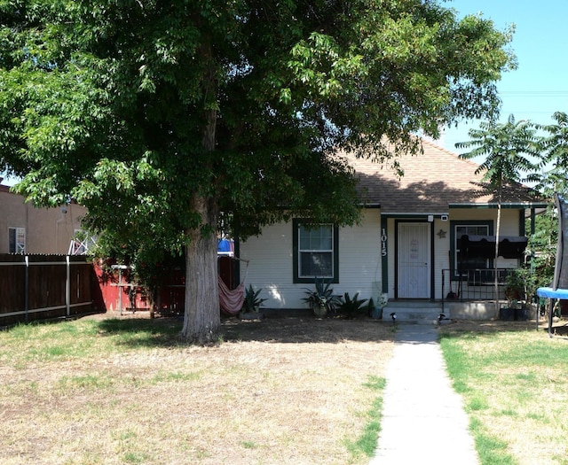 view of front of house with a trampoline and a front lawn