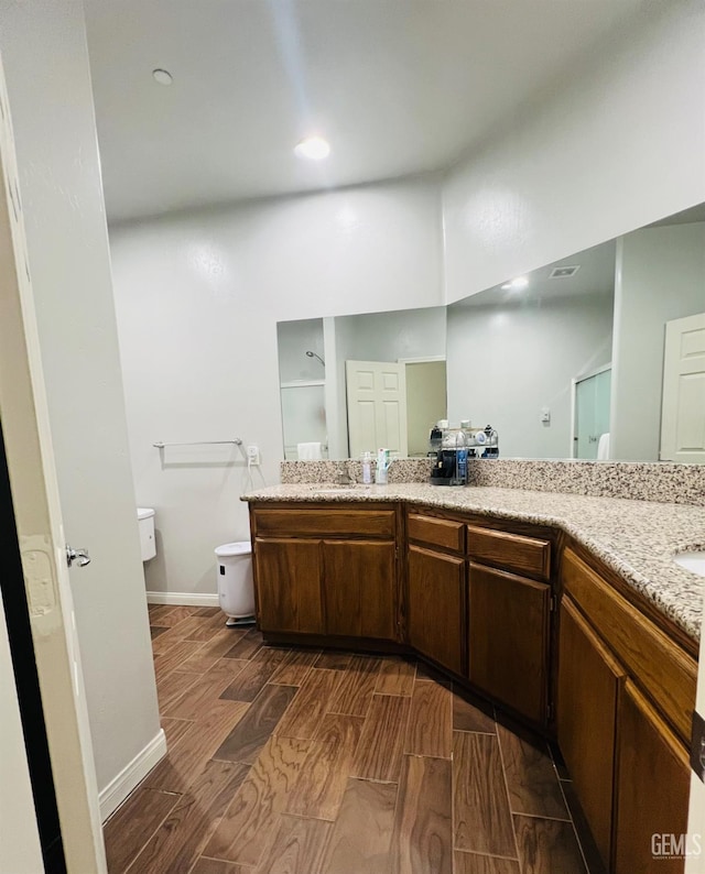 318 Smoke Tree Ct, Wasco, CA 93280 - bathroom with toilet, double vanity, wood finished floors, and baseboards