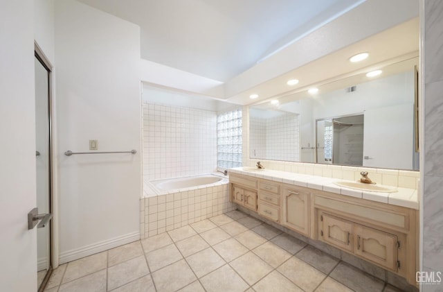 bathroom featuring vanity, tile patterned flooring, and a relaxing tiled tub