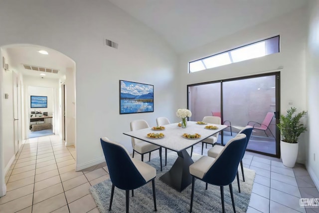 tiled dining space featuring high vaulted ceiling