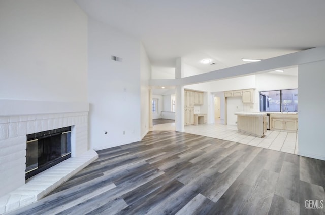 unfurnished living room with vaulted ceiling, a fireplace, and hardwood / wood-style floors