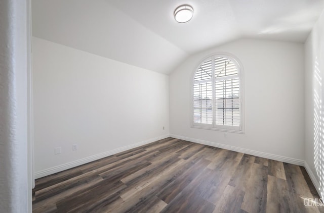 spare room with dark wood-type flooring and lofted ceiling