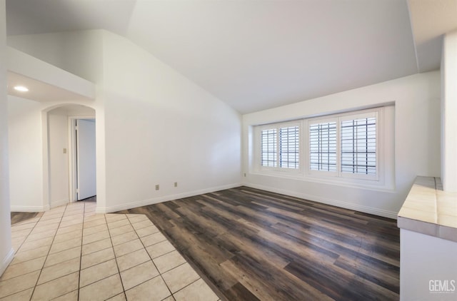 empty room featuring light wood-type flooring and vaulted ceiling