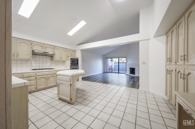 kitchen with a center island, a fireplace, backsplash, white gas cooktop, and cream cabinetry