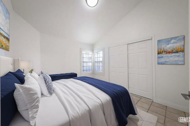 tiled bedroom featuring lofted ceiling and a closet