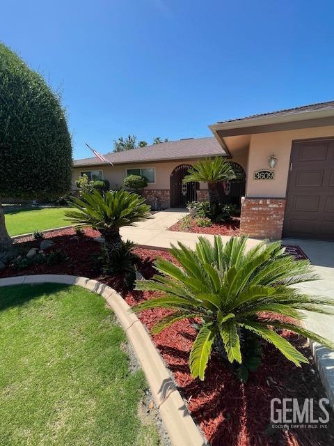 3609 Planz Rd, Bakersfield, CA 93309 - ranch-style home featuring stucco siding, an attached garage, brick siding, and a front yard