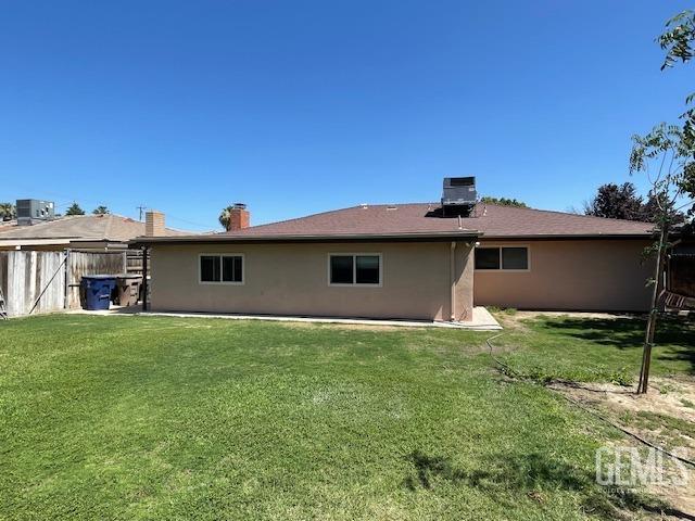 3609 Planz Rd, Bakersfield, CA 93309 - rear view of house featuring fence, stucco siding, a yard, and a chimney