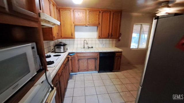 113 Easy St, Bakersfield, CA 93308 - kitchen featuring under cabinet range hood, white appliances, a sink, tasteful backsplash, and tile counters