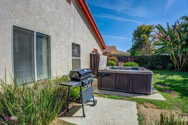 view of patio with fence, a grill, and a hot tub