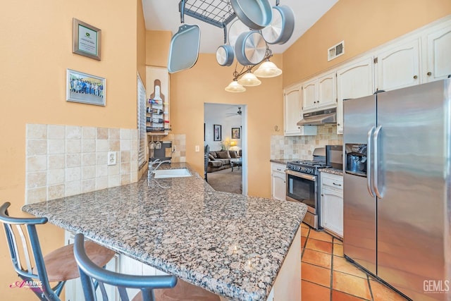 kitchen featuring visible vents, under cabinet range hood, a peninsula, stainless steel appliances, and a sink