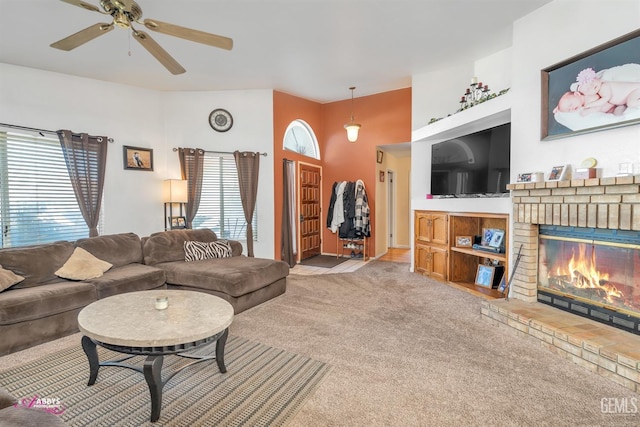 carpeted living area with a brick fireplace and ceiling fan