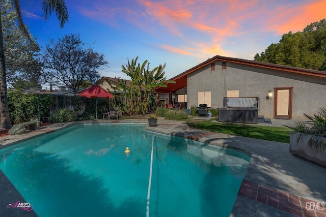 pool at dusk featuring fence, a patio area, and a fenced in pool