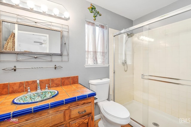 full bathroom featuring toilet, a stall shower, and vanity