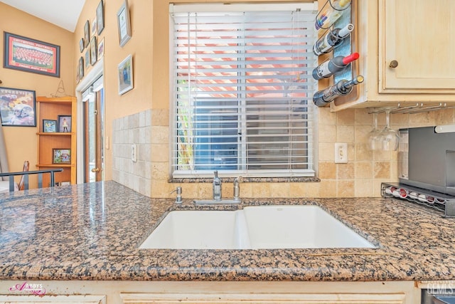 kitchen with decorative backsplash, dark stone countertops, and a sink