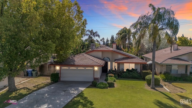 view of front of house featuring a tile roof, a front yard, stucco siding, a garage, and driveway