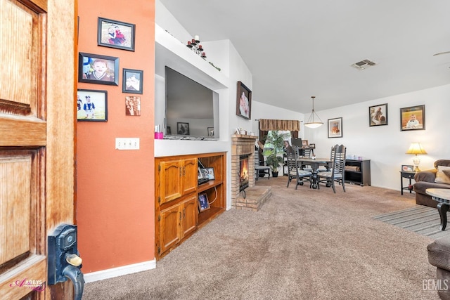 interior space featuring lofted ceiling, a brick fireplace, light colored carpet, and visible vents