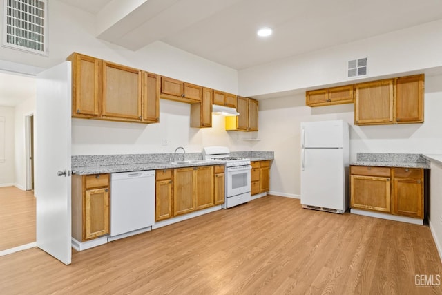 kitchen featuring light stone countertops, sink, white appliances, and light wood-type flooring