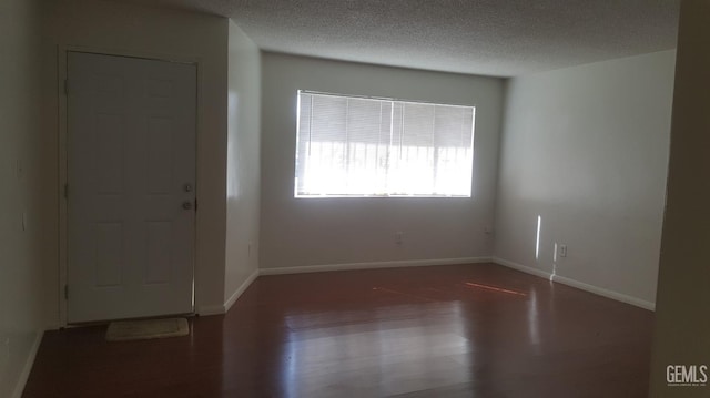 empty room featuring baseboards, a textured ceiling, and wood finished floors