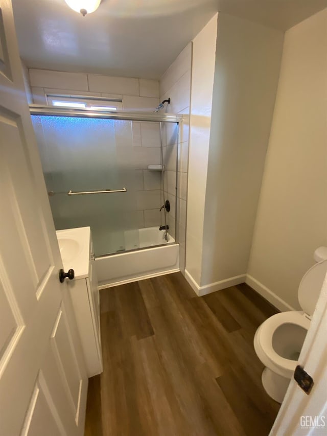 full bathroom featuring toilet, vanity, enclosed tub / shower combo, and hardwood / wood-style flooring