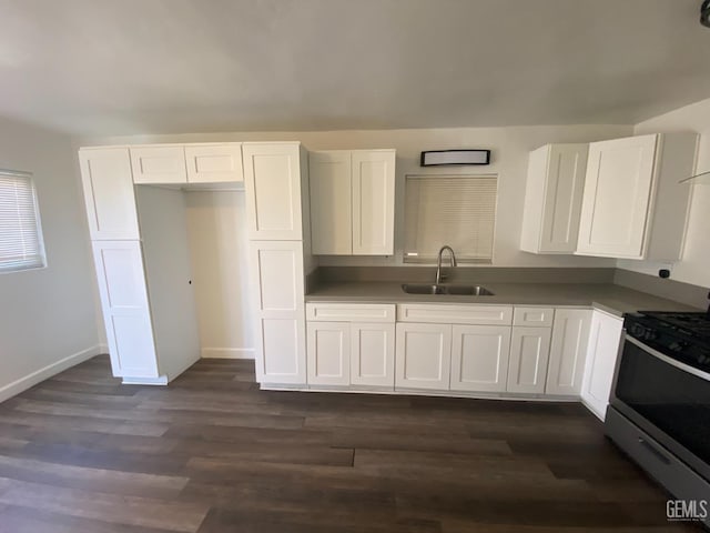 kitchen with white cabinets, sink, stainless steel stove, and dark wood-type flooring