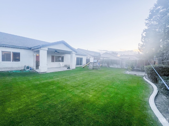 view of yard featuring a playground, a patio, a fenced backyard, and ceiling fan