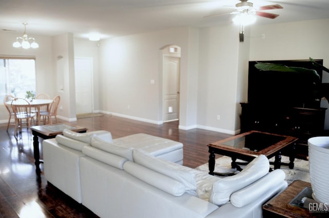 living room featuring ceiling fan with notable chandelier, baseboards, and wood finished floors