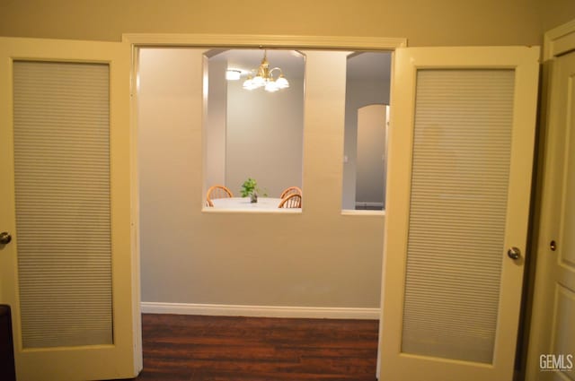 hall with an inviting chandelier, baseboards, and wood finished floors