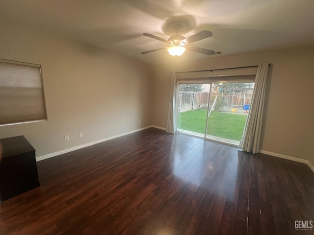 unfurnished room with baseboards, dark wood finished floors, and a ceiling fan