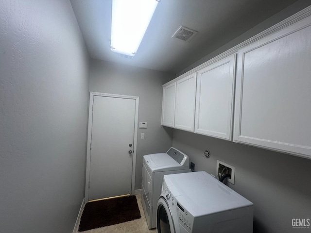 clothes washing area with visible vents, cabinet space, and washer and dryer